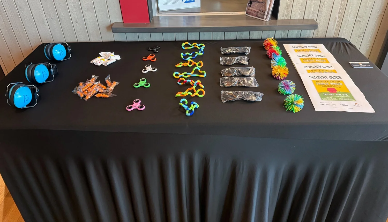A sensory kit: headphones, fidgets, sunglasses, and printed Sensory Guides